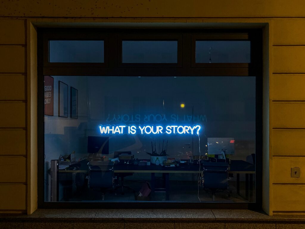 Neon Sign In Window That Says, 'What Is Your Story To Visualize Storytelling Career Day Ideas